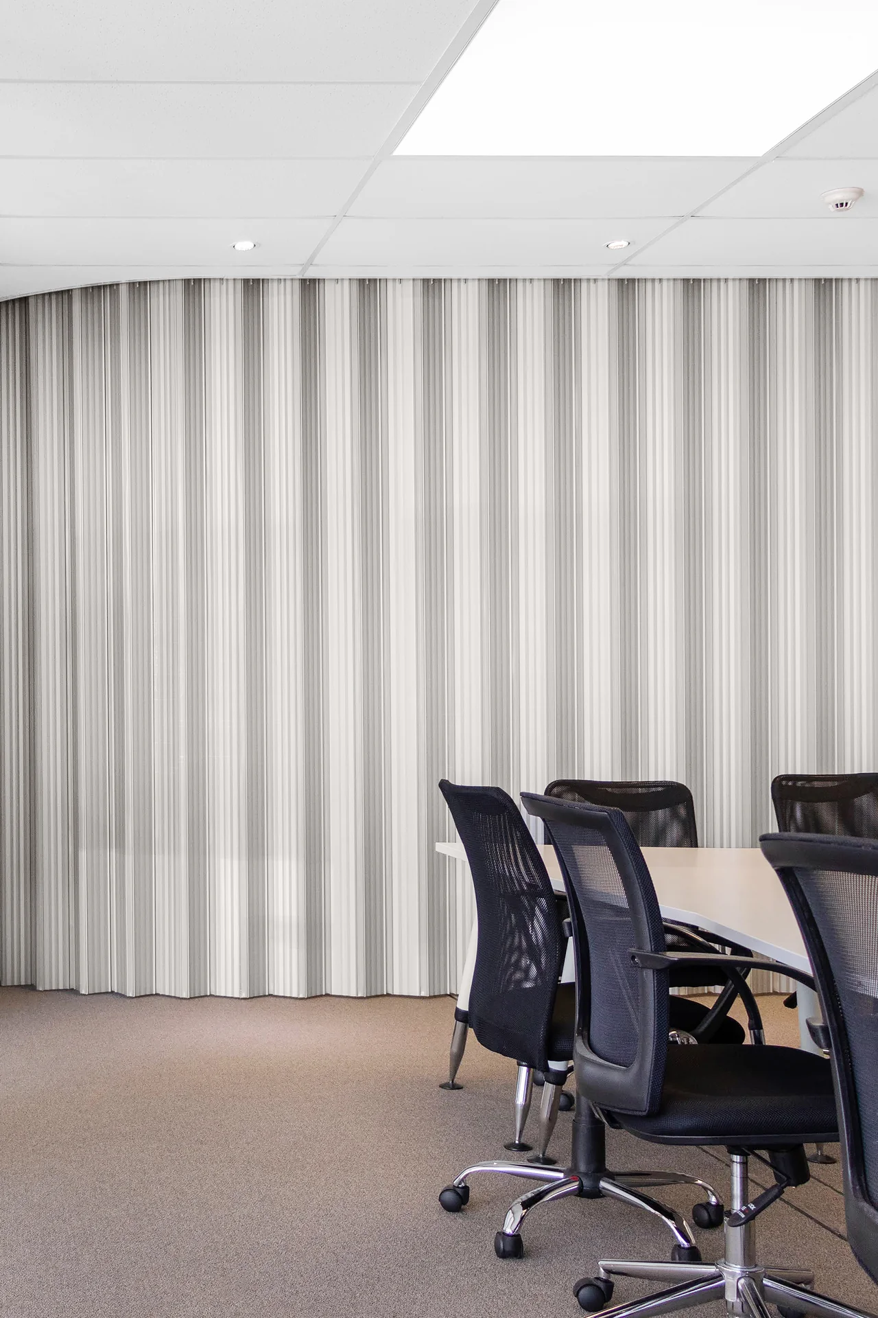 Curved DuraFlex accordion partition dividing a modern office meeting room